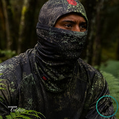 Person wearing camouflage clothing and a balaclava in a forest setting