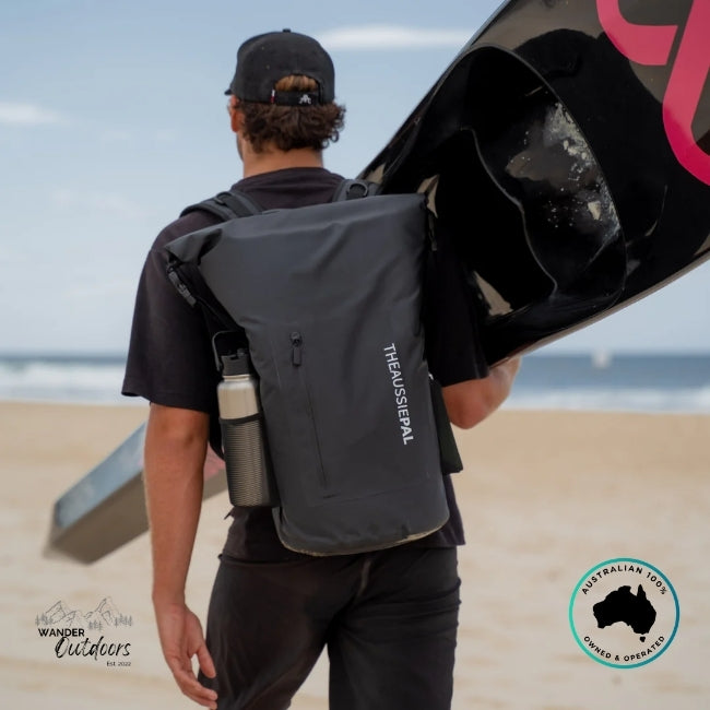Person carrying a backpack with 'The Aussie Pal' branding on a beach.