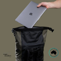 Person placing a laptop into a black backpack on a beige background