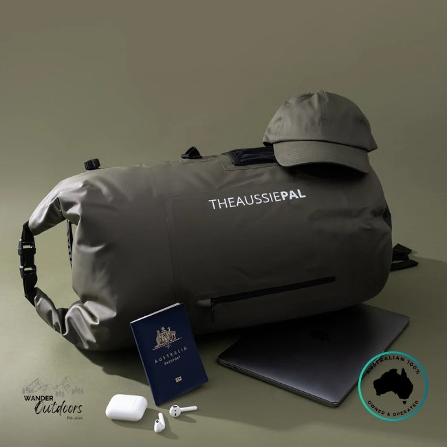 Gray duffel bag with 'THEAUSSIEPAL' branding, Australian passport, phone case, and earbuds on a beige background.