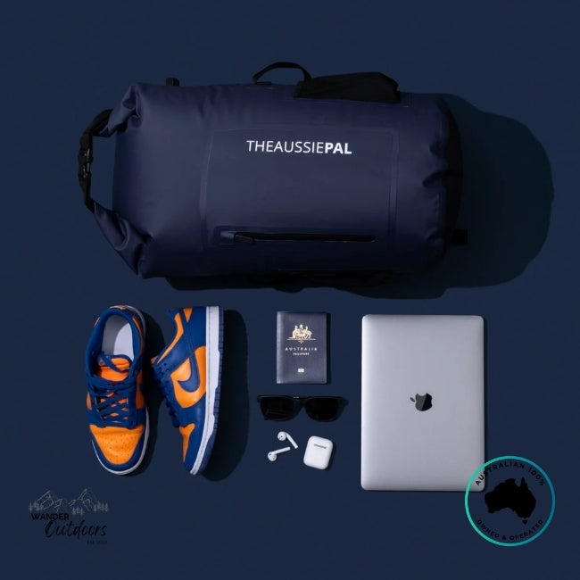 Collection of items including a navy bag, orange and blue sneakers, laptop, and other accessories on a dark background.