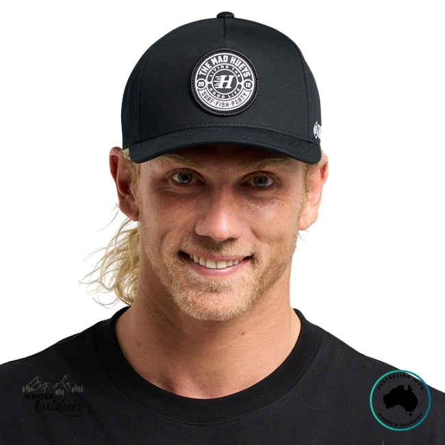 Man wearing a black cap with The Mad Hueys Logo front on, on a white background