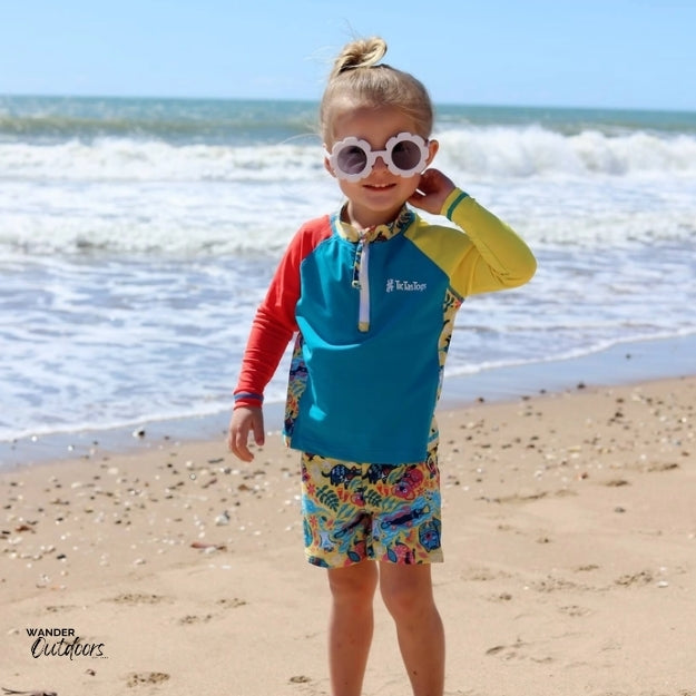 A girl at the beach wearing aussie animalia rashie with sunglasses on.