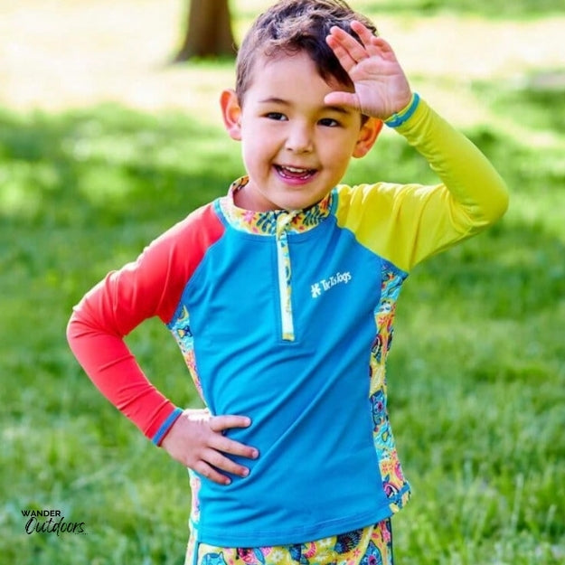 A boy on the grass wearing the aussie animalia rashie with his arm in the air