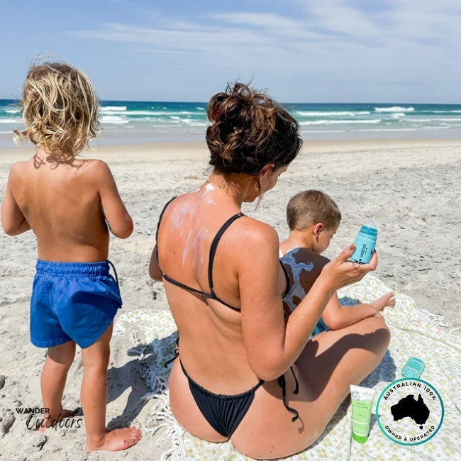 Mother applying sunscreen to kids using Wotnot Refillable Roll-On Applicator during a beach day.