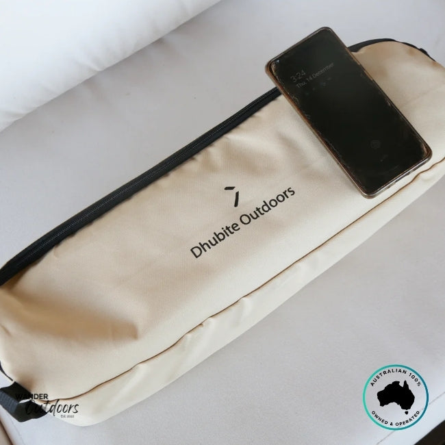 Close-up of the Dhubite Outdoors beige chair storage bag with logo printed on the front, phone resting on top.