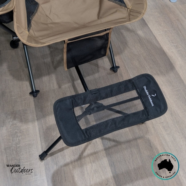 Close-up of the Dhubite Outdoors Camp Chair Foot Rest in black mesh fabric, attached to the base of the tan chair, highlighting adjustable frame and matching materials.