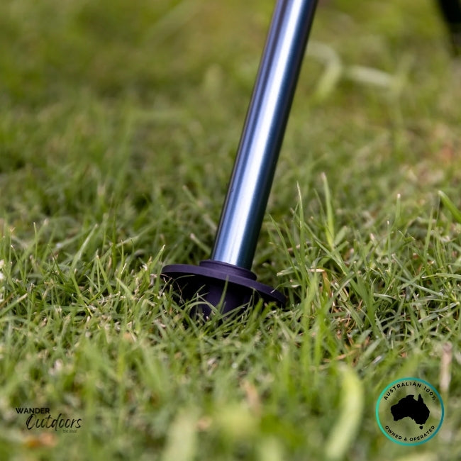 Detailed view of the Dhubite Outdoors chair foot stopper on grassy ground, highlighting the wide base design that prevents sinking in soft surfaces.