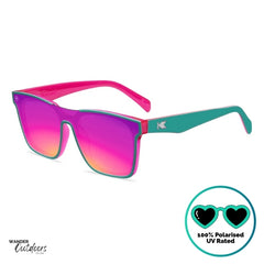 Knockaround Afters Miami Sunglasses with pink lenses and teal frames on a white background, birds eye view. 