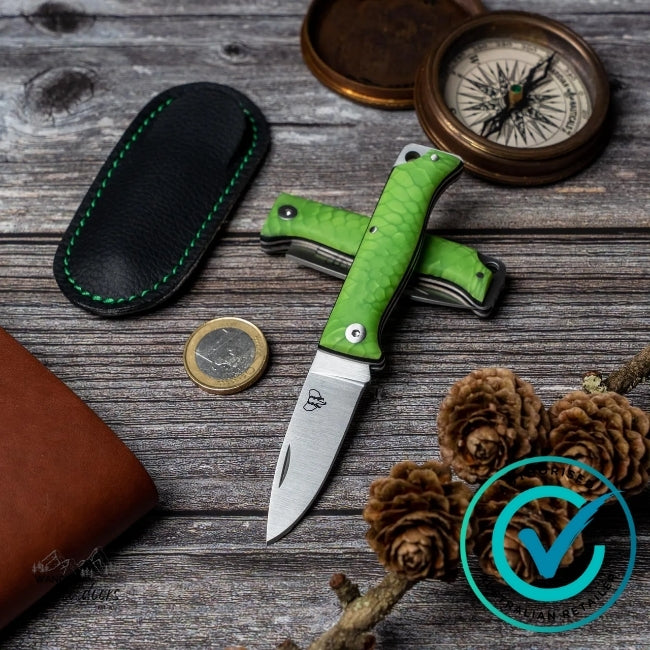 Green pocket knife on a wooden surface with a compass, coin, and wallet.