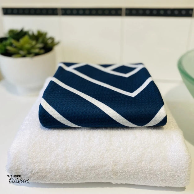 Newlyfe Waffle Weave Bath Towel Navy compact folded on top of bulky cotton towel.