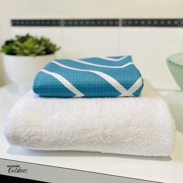 Newlyfe Waffle Weave Bath Towel Teal Compact folded on top of bulky cotton towel