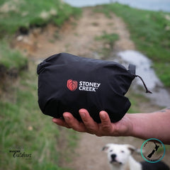 Person holding a packed Stoney Creek Recreational (Stow it) Jacket in Black with a blurred natural background
