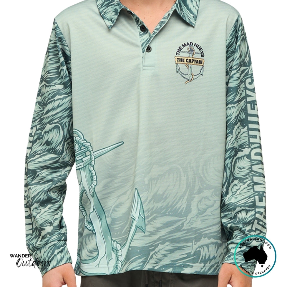 Front view of The Mad Hueys Croc Captain Youth UPF 50+ Fishing Jersey in faded dust, featuring front chest logo and all-over ocean pattern sleeves.