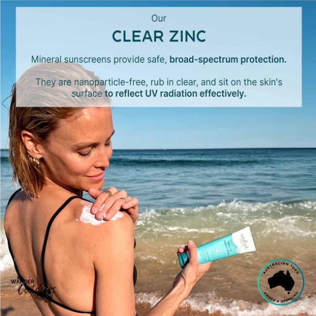 Woman applying Wotnot Naturals SPF 50 Sunscreen on shoulder at the beach with overlay text describing broad-spectrum clear zinc protection.