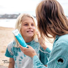 Mother applying Wotnot Naturals SPF 50 Sunscreen to her child’s face at the beach.