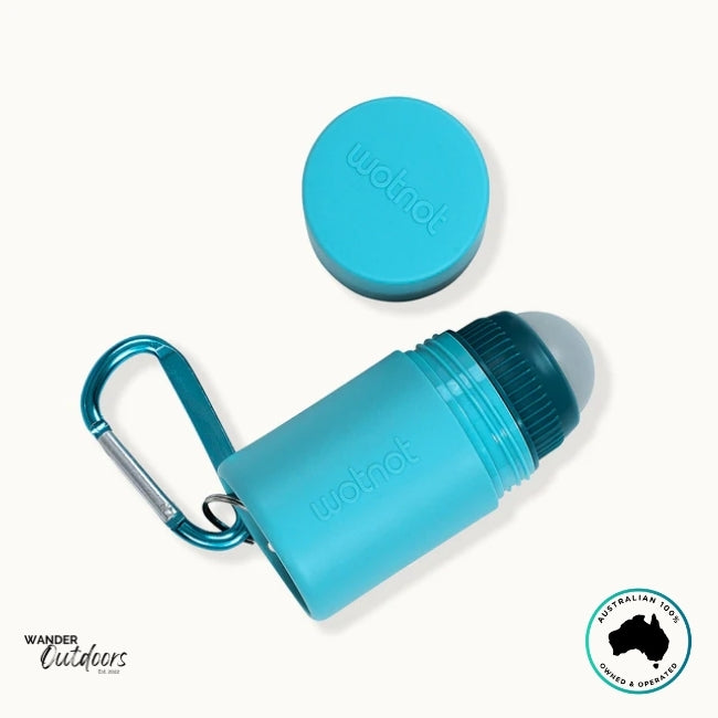 Flat-lay of Wotnot Refillable Sunscreen Roll-On Applicator with lid removed and carabiner visible.